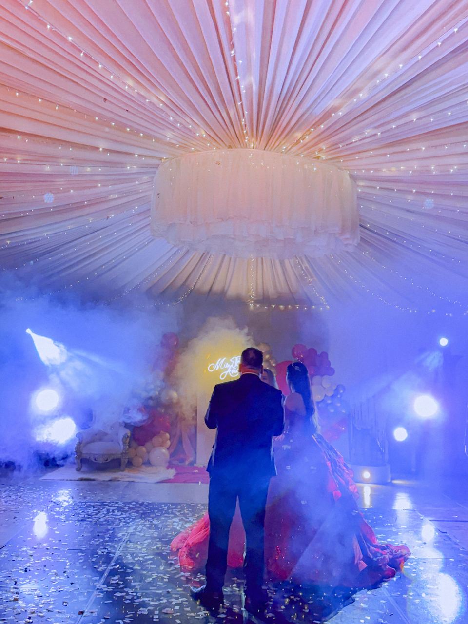 Baile de quinceañera con máquina de humo, haces de luz de colores y confeti sobre la pista